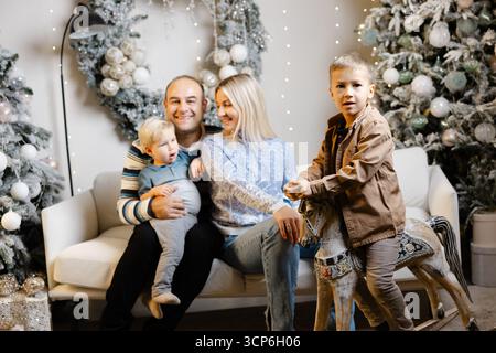 Fröhliche Familie feiert den weihnachtsmorgen, indem sie gemeinsam Geschenke öffnet und lacht Stockfoto