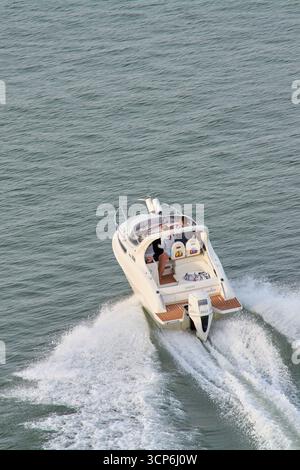 Venedig. Italien - 24. September 2025: Ein Hochwinkelblick fängt eine elegante weiße Cabin Cruiser Motoryacht ein, die über das offene Meer rasant und ein Powerfu hinterlässt Stockfoto