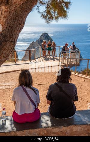 Junges Paar im Urlaub zusammen im Schatten eines Baumes an einem Aussichtspunkt auf der griechischen Ionischen Insel Zante oder Zakynthos in Griechenland Stockfoto
