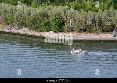 Venedig. Italien - 24. September 2025: Ein Blick aus der Höhe zeigt ein kleines Motorboot mit ein paar Leuten, die eine gemütliche Bootstour entlang einer ruhigen Wasserstraße genießen Stockfoto