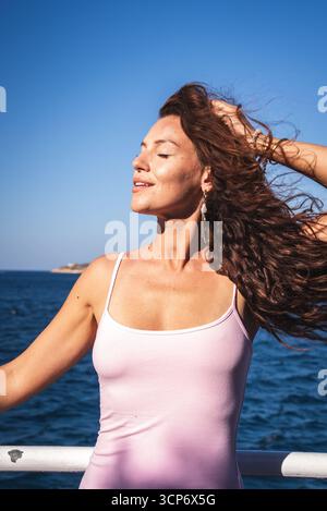 Frau lächelt am Meer mit Insel im Hintergrund, Kreta Stockfoto