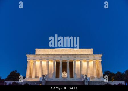 Lincoln Memorial Washington DC USA // WASHINGTON DC — das Lincoln Memorial, ein neoklassizistisches Denkmal zu Ehren des 16. US-Präsidenten Abraham Lincoln, wird vor einem tiefblauen Dämmerhimmel beleuchtet. Das vom Architekten Henry Bacon entworfene Denkmal zeigt eine sitzende Statue von Lincoln vom Bildhauer Daniel Chester French, die durch die Kolonnade sichtbar ist. Das Gebäude besteht aus Marmor und Granit und ist ein markantes Wahrzeichen der National Mall. Sie wurde 1922 geweiht und dient als Symbol der amerikanischen Einheit und Freiheit. Stockfoto