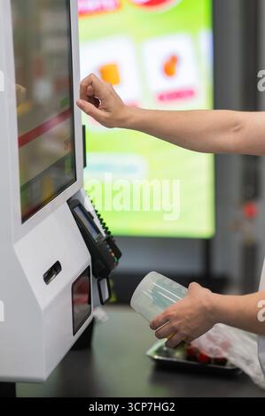 Eine Frau scannt Artikel an einer Selbstkasse. Stockfoto