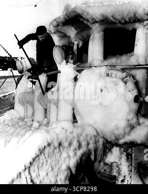 Ice Covered Trawler -- Jim Deady, ein Crewmitglied des Fischtrawlers Dorchester, benutzt heute eine Brechstange, um Eis vom Pilothaus am Boston Fish Pier zu zerschlagen. Der Trawler kehrte nach einem sechstägigen Angelausflug mit 80.000 Pfund Grundfisch zurück, der bei nahezu null Wetter vor der Georges Bank gefangen wurde. Februar 1951. (Foto von AP Wirephoto). Stockfoto