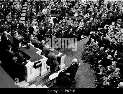 Churchill spricht vor dem Kongress -- Premierminister Winston Churchill hält sich in einer vertrauten Geste an seinem Revers fest (links unten auf Rostrum), spricht am 19. Mai auf dem Kongress an und verspricht Großbritanniens Unterstützung im Krieg gegen Japan. Kongressabgeordnete und Washingtons höchste Würdenträger packten das Haus. Mai 1943. (Foto von zugehörigem Pressefoto). Stockfoto