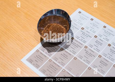 TOKIO, JAPAN - 27. OKTOBER 2024: Nahaufnahme der gemahlenen gerösteten Kaffeebohnen mit Menü des Mameya Koffee Shops, einem besonderen Café in Tokio. Stockfoto