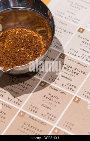 TOKIO, JAPAN - 27. OKTOBER 2024: Vertikales Bild der gemahlenen gerösteten Kaffeebohnen mit Menü des Mameya Koffee Shops, einem speziellen Coffee Shop in Tokio. Stockfoto