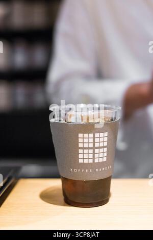 TOKIO, JAPAN - 27. OKTOBER 2024: Vertikales Bild von gefiltertem Kaffee in einer Plastiktasse im berühmten Mameya Coffee Shop im Zentrum von Tokio Stockfoto