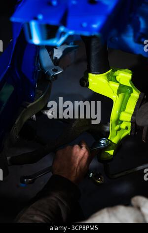 Einbau der Rennscheibenbremse mit leuchtend grünem Achsschenkel an der Aufhängung. Einbau der Vorderradaufhängung und der Bremsscheibe. Einbau der Performance-Federung Stockfoto