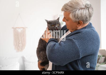 Seniorenmann mit süßer Katze zu Hause Stockfoto