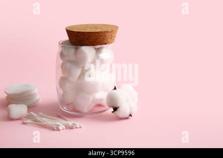 Becher mit Wattebällchen, Tupfern, Pads und Blume auf rosafarbenem Hintergrund Stockfoto