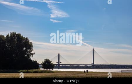 Die Mersey Gateway Bridge, die den Mersey überspannt und von Spike Island in Widnes an einem klaren Tag aus gesehen wird, wo Menschen im Vordergrund laufen Stockfoto