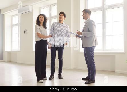 Ein Paar, das mit einem Makler in einem neuen Haus spricht und bereit ist, Hausbesitzer zu werden. Stockfoto