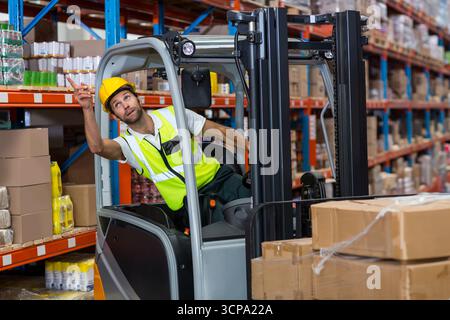 Der Gabelstapler hebt die gewickelte Palette aus dem oberen Regal des Lagers mit blauen und orangefarbenen Regalen Stockfoto