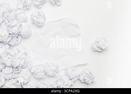 Zerknittertes weißes Papier, das auf einer sauberen Oberfläche verstreut ist und eine minimalistische Komposition schafft Stockfoto