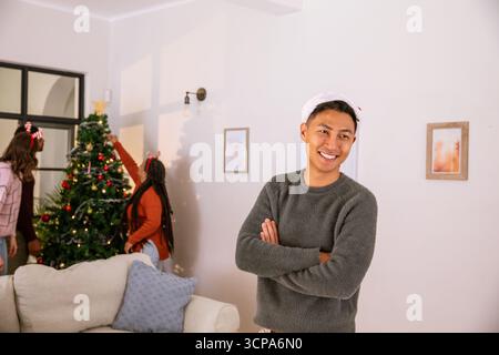 Verschiedene Freunde im weihnachtsmann, die den weihnachtsbaum schneiden, einen Stern im Wohnzimmer setzen, Kopierraum Stockfoto