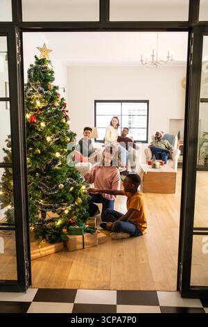 Vielfältige Familiendekoration des weihnachtsbaums auf dem Wohnzimmerboden mit Ornamenten, Lichtern, Kopierraum Stockfoto