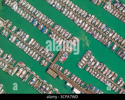 Blick aus der Vogelperspektive auf Boote und Yachten in der Umarmung des Yachthafens, eine Symphonie aus weiß vor dem pulsierenden türkisfarbenen Wasser, Sausalito, Kalifornien, USA. Stockfoto