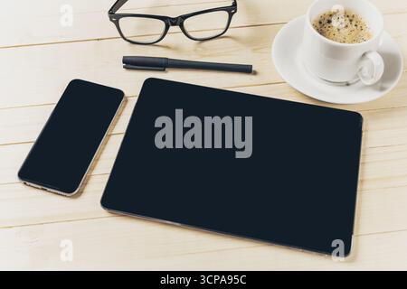Arbeitsbereich mit Laptop, Smartphone, Kaffee und Gläsern auf Holztisch Stockfoto