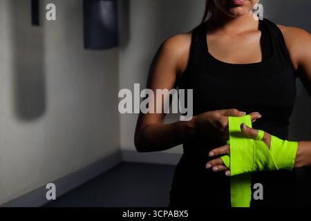 Frau wickelt Hände mit neongrünen Boxhüllen in der Turnecke, indem sie Tasche, Kopierraum Stockfoto