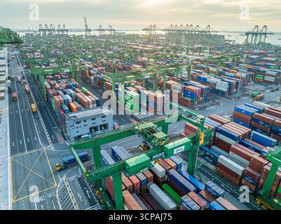 Singapur, Singapur - 06. Dezember 2024: Aus der Vogelperspektive des Pasir Panjang Terminals zeigt sich eine Symphonie aus gestapelten Containern und hoch aufragenden Kranen unter einem weichen, diffusen Sonnenlicht. Stockfoto