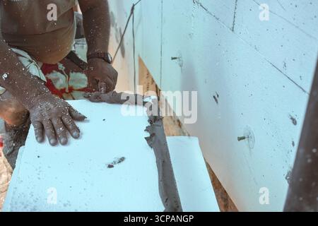 Installation der weißen Polystyrol-Wärmedämmung, Detail auf Arbeiter Hand legen grauen Kleber Zement auf weißen Brettern Stockfoto