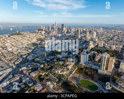 Aus der Vogelperspektive blickt man auf eine weitläufige Stadtlandschaft, in der moderne Wolkenkratzer den Horizont durchdringen und die berühmte Bay Bridge als Wächter in der Ferne steht, San Francisco, Kalifornien, USA. Stockfoto