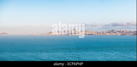Die Skyline von San Francisco schimmert aus der Vogelperspektive unter weichem Himmel über der Bucht, mit Alcatraz Island, einem entfernten Wächter in San Francisco, Kalifornien, USA. Stockfoto