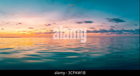 Atemberaubender farbenfroher Sonnenuntergang über dem Meer mit dramatischem Himmel, glühenden Wolken, goldenen Sonnenstrahlen, endlosem Horizont, traumhafter friedlicher Natur Hintergrund, inspirierend Stockfoto