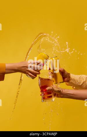 Drei Bierdosen und Glasspritzer-Explosion auf gelbem Hintergrund. Mockup für Text, Werbung Stockfoto