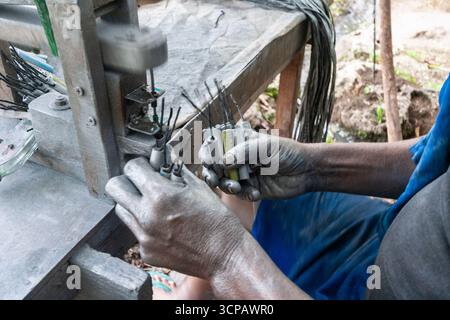 Männlicher Cebuano-Arbeiter, der Feuerwerkskörper für das neue Jahr in einem kleinen Freiluftbetrieb in Mactan Island, Cebu, zusammenbaut Stockfoto