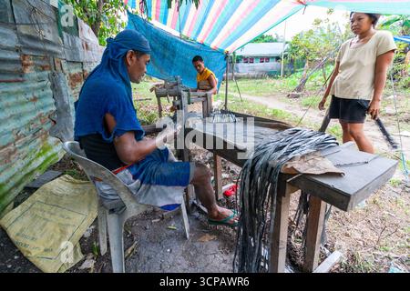 Männliche Cebuano-Arbeiter, die Feuerwerkskörper für das neue Jahr in einem kleinen Freiluftbetrieb in Mactan Island, Cebu, zusammenbauen Stockfoto