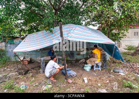 Männliche Cebuano-Arbeiter, die Feuerwerkskörper für das neue Jahr in einem kleinen Freiluftbetrieb in Mactan Island, Cebu, zusammenbauen Stockfoto