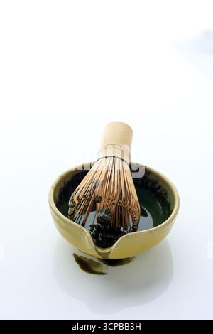 Japanische Teeschale mit Matcha Chasen oder Bambus Schneebesen, eine Ausrüstung für die Zubereitung von Matcha Green Tea auf weißem isoaltem Tisch. Stockfoto