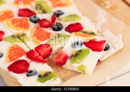 Hausgemachte gefrorene Joghurtrinde mit Kiwi, Heidelbeere, Orange und Erdbeere. Stockfoto
