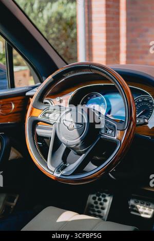 Vilnius, Litauen - 9. September 2025 - Innenraum von Bentley Bentayga mit hölzernem Lenkrad und blauen Lederdetails Stockfoto