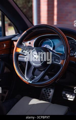 Vilnius, Litauen - 9. September 2025 - Innenraum von Bentley Bentayga mit hölzernem Lenkrad und blauen Lederdetails Stockfoto
