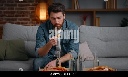 Kaukasischer Mann mittleren Alters frustriert enttäuscht Mann zu Hause Party abgesagt mit Pizza Chips Stress allein einsamer männlicher Kerl auf der Couch leidet ohne Nein Stockfoto