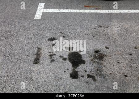 Ölflecken auf einem Parkplatz in Spanien. Bodenverschmutzungsproblem. Motorölflecken auf Asphaltflächen. Stockfoto