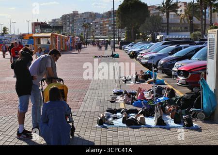 SANTA POLA, SPANIEN - 17. APRIL 2025: Menschen sehen gefälschte Designertaschen, die illegal an einem provisorischen Straßenstand in Santa Pola in der Provinz Alicante, Spa, verkauft werden Stockfoto