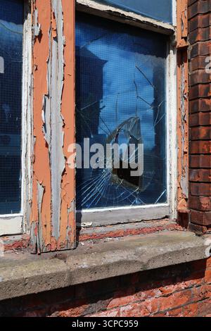 Altes Industriegebäude in Belfast City, Nordirland. Glasbruch eines drahtverstärkten Fensters in einem verlassenen Gebäude. Stockfoto
