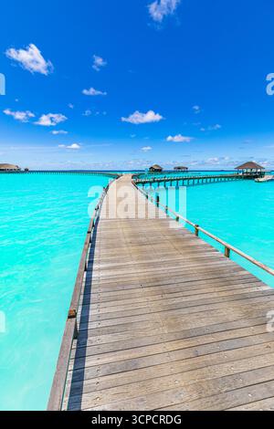Atemberaubende Wasservillen in den Malediven Inseln Resorts mit ruhigem Pier ruhigem Meer Horizont unter sonnigem blauem Himmel. Beliebte tropische Sommerferienlandschaft Stockfoto