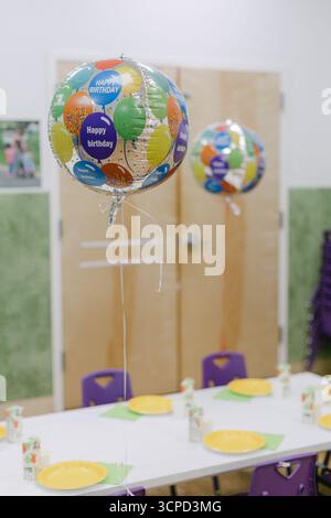 Helle Ballons schweben über einem Partytisch, der für eine fröhliche Geburtstagsfeier in einer fröhlichen Umgebung dekoriert ist. Stockfoto