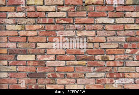 Ziegelwand aus alten, verschiedenfarbigen Klinkerziegeln mit grob bearbeitetem Mörtel Stockfoto