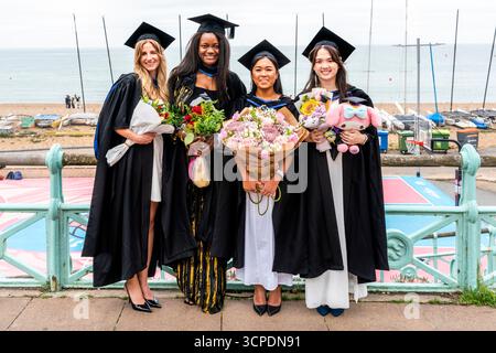 Studenten der University of Brighton posieren für Ein Foto am Meer nach ihrer Abschlussfeier in Brighton, East Sussex, Großbritannien. Stockfoto