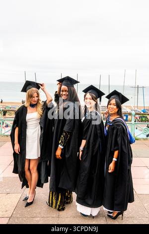 Studenten der University of Brighton posieren für Ein Foto am Meer nach ihrer Abschlussfeier in Brighton, East Sussex, Großbritannien. Stockfoto