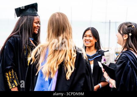 Studenten der Universität Brighton plaudern nach ihrer Abschlussfeier am Meer, Brighton, East Sussex, Großbritannien. Stockfoto
