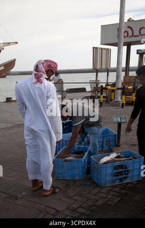 Ein Mann aus oman kauft Fisch von Fischern im Hafen sur Dhow sur oman Sultanat oman Stockfoto