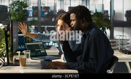 Manager beaufsichtigt die Arbeit des Buchhalters, indem er Finanzdaten auf den PC eingibt und Berichte überprüft. Vorgesetzter, der den Fortschritt eines Mannes überwacht, der im Büro arbeitet und Daten abgleicht, Kamera A Stockfoto