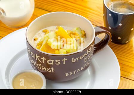 Köstliches Haferbrei mit Früchten und Nüssen serviert an einem gemütlichen Frühstückstisch Stockfoto